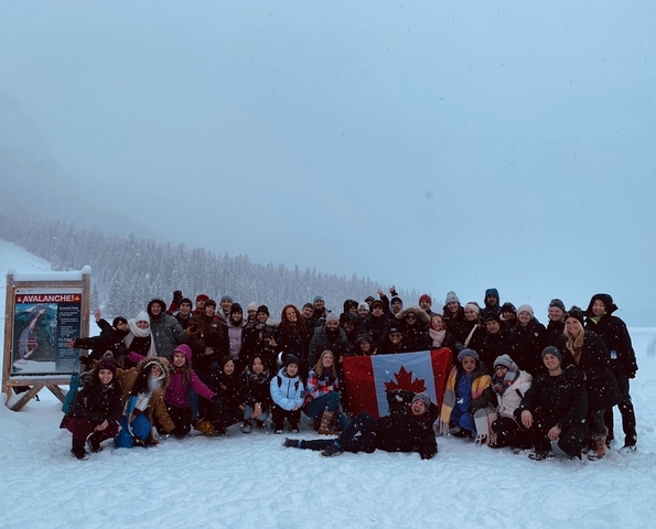       Group photo in a snowy landscape with people holding a Canadian flag.
  