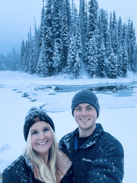       Couple standing on snow with trees in the background.
  