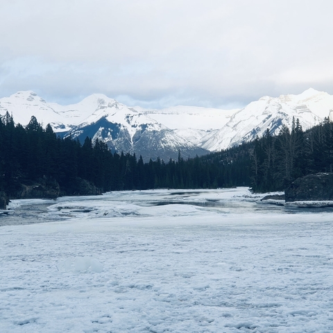      Frozen river with mountainous terrain in the background.
  