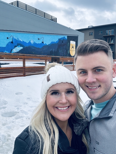       Close-up of a couple near a snowy setting with a mural in the background.
  
