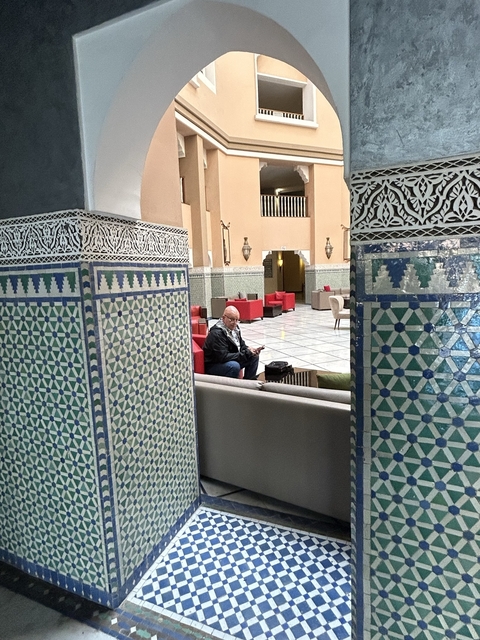       Interior with patterned pillars and a person sitting.
  