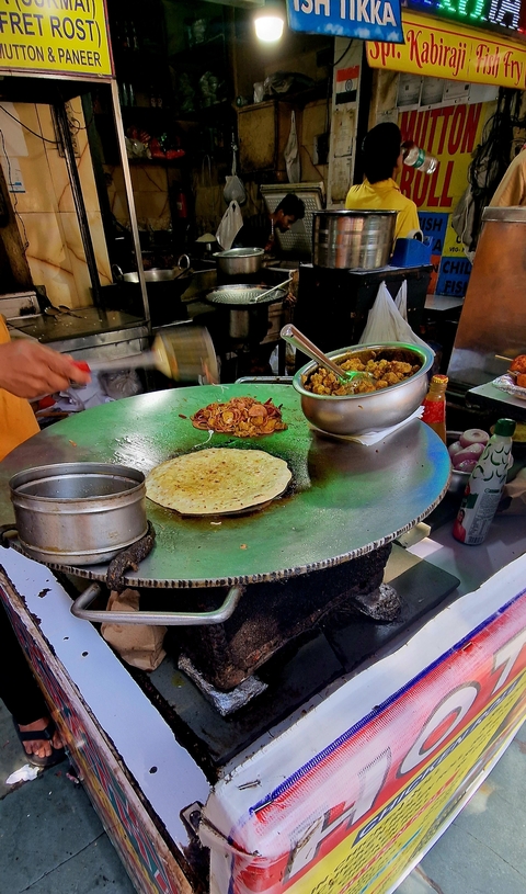 Street food vendor preparing food on a large flat pan.