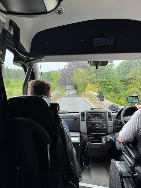Inside a vehicle with a view of a road and trees.