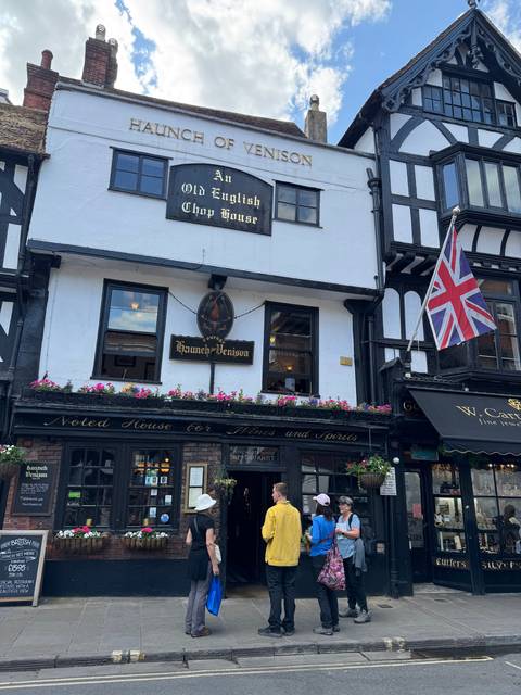 Old English pub with people gathered outside.