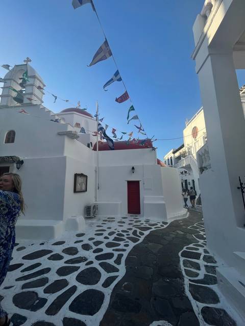 Traditional Greek street with white buildings and flags.