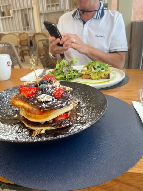 Plates of food on a wooden table, person taking photo.