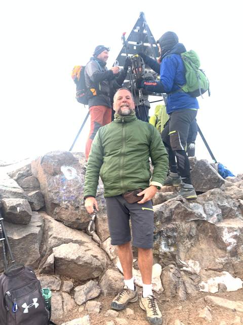       People posing on a mountain summit.
  
