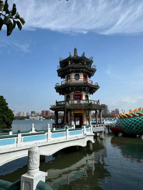 Pagoda by the water with distant buildings in the background.