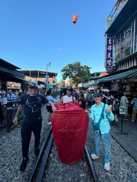 Group of people launching a red lantern on a railway track.