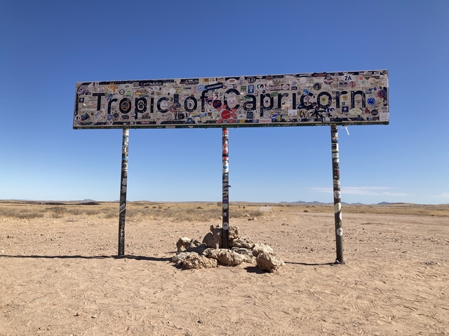       A sign for the Tropic of Capricorn in a dry, barren landscape.
  