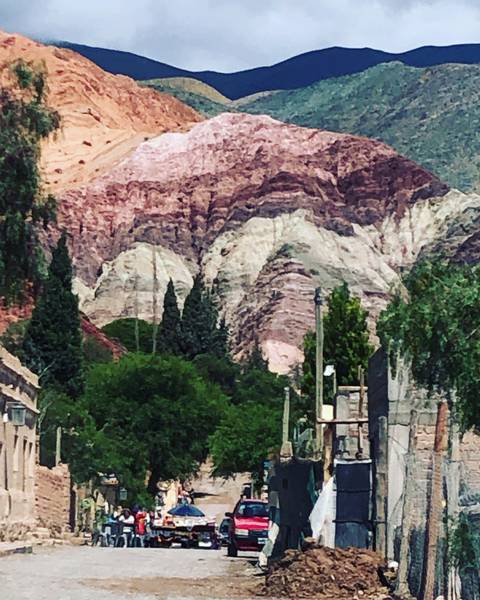 Colorful layered mountains with greenery at the base, likely in Purmamarca.