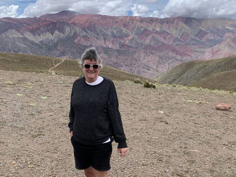 Person standing in front of colorful layered mountains, likely in Purmamarca.