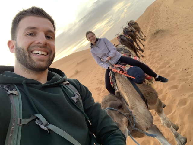 People riding camels on a desert excursion.