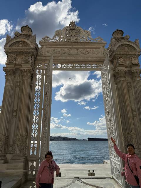       Elegant gate with people and a view towards the sea.
  