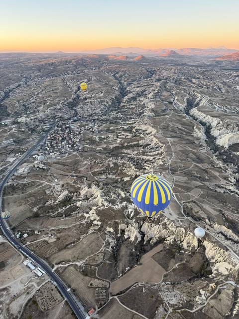       Hot air balloons over a rugged landscape at sunrise.
  