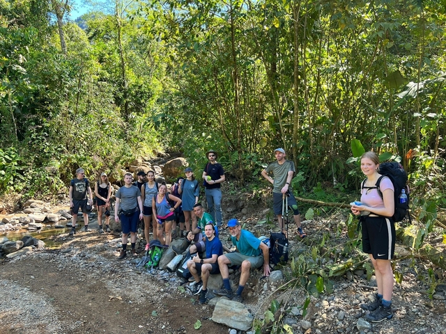 Large group of hikers posing in a forest area.