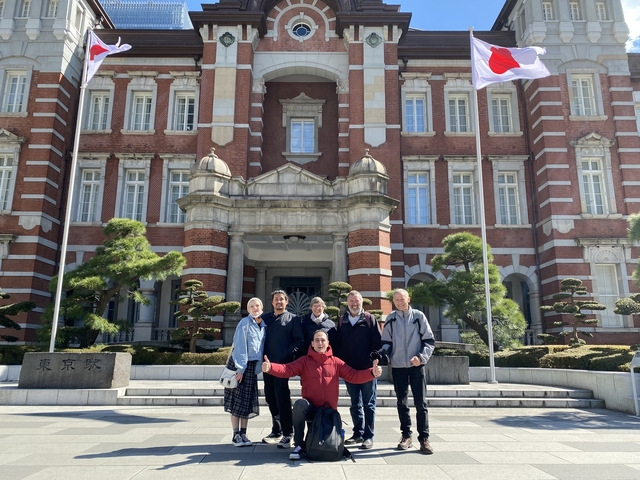 People posing in front of a historic building with Japanese flags.