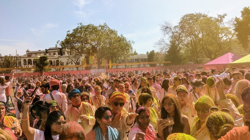       Large group of people celebrating with colorful powder.
  