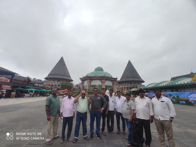 Group posing in front of a historic building with triangular roofs.