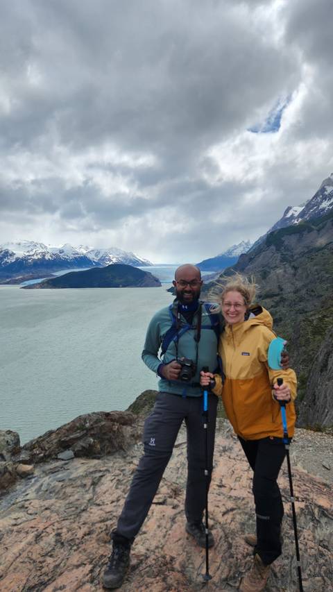       Two hikers posing on a rocky overlook with a vast body of water.
  