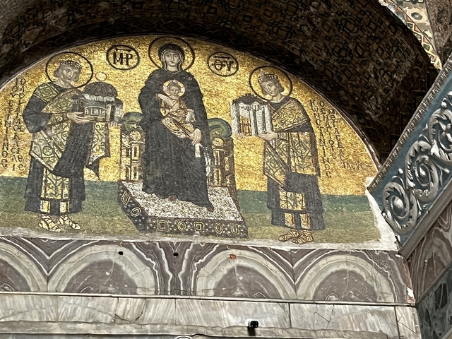 Detailed mosaic art on a historic wall inside a building.