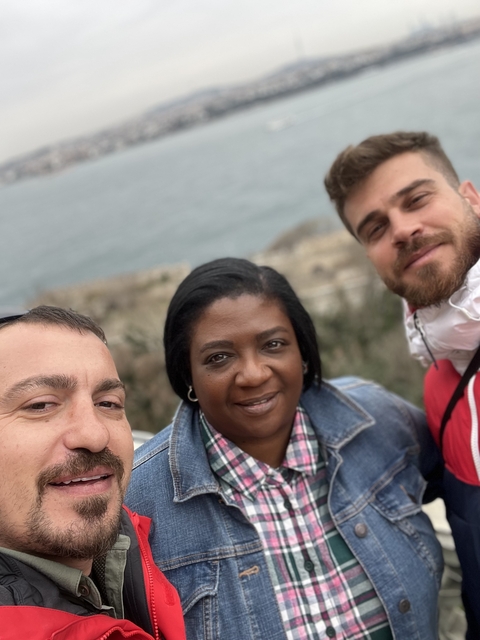       Three people taking a close-up photo with the sea in the background.
  
