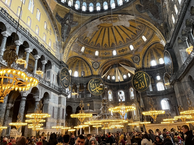       Interior view of a grand dome with ornate decorations and lights.
  