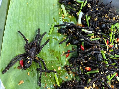 Cooked tarantulas on a banana leaf with spices and herbs.