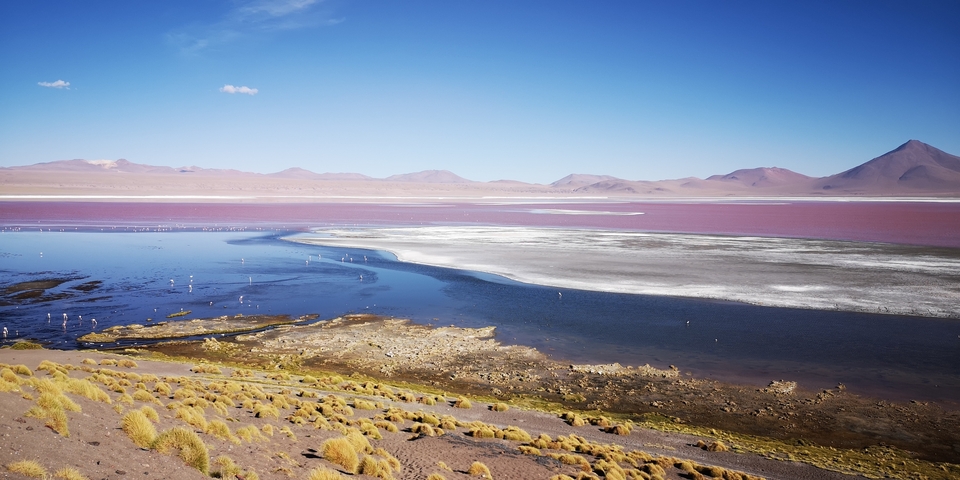 Vast desert landscape with a salt flat and distant mountains.