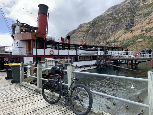       Docked steamboat by a lakeside with hills in the background.
  
