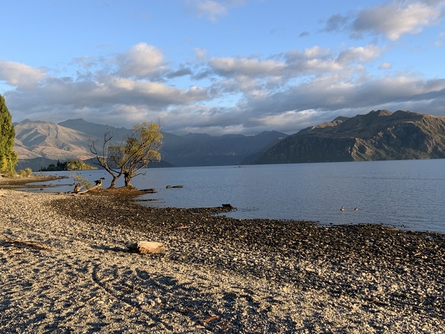      Lake surrounded by mountains under a cloudy sky.
  