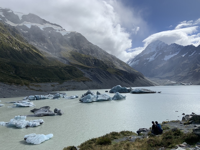       Glacier lake with floating icebergs surrounded by mountains.
  