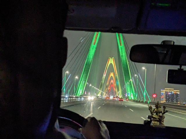       Night view of a bridge lit in vibrant colors.
  