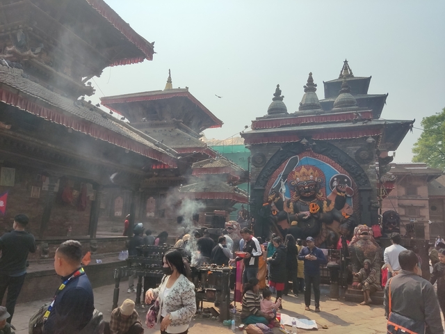       People visiting a temple with large sculptures.
  