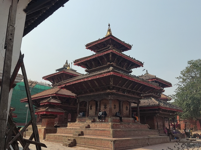       Traditional multi-tiered temple with people sitting on the steps.
  