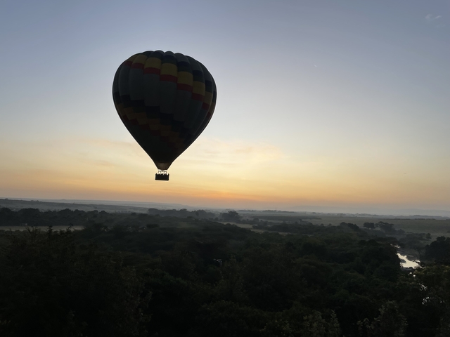 Hot air balloon silhouetted against a sunrise over a landscape.