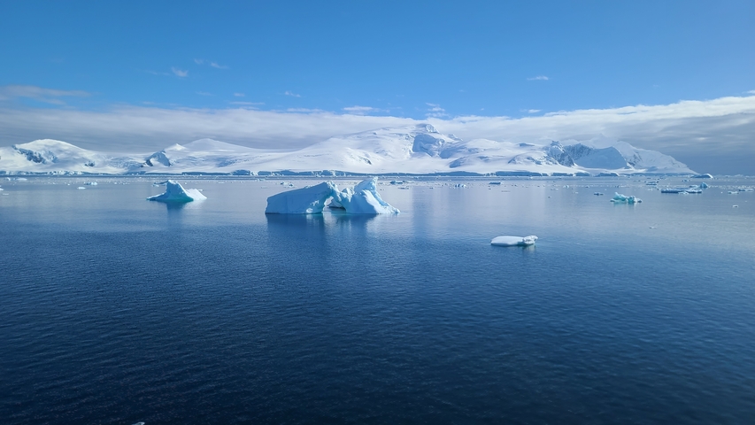 Icy landscape with clear blue sky and floating icebergs.