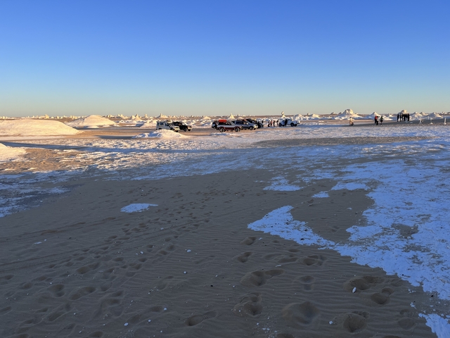 Off-road vehicles parked in a desert area with people nearby.