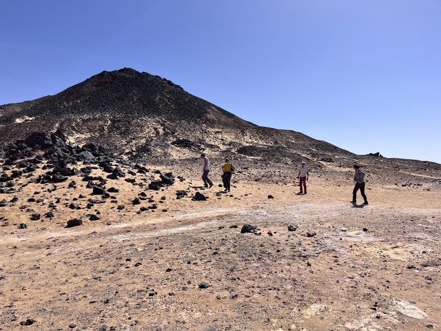 Group of people walking across a rocky desert landscape.