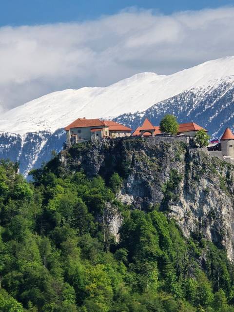 A scenic view of a mountain with a building on the cliffside.