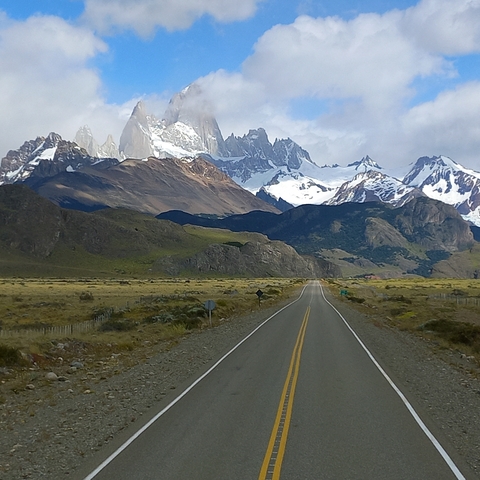       Long road leading towards snowy mountains.
  