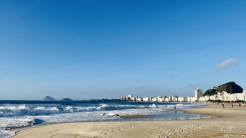       Beautiful beach with ocean waves and city skyline.
  
