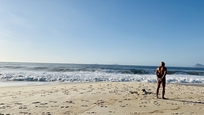 Lone man standing on a vast sandy beach.