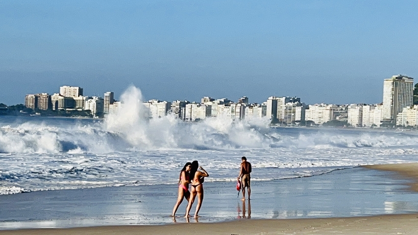 People enjoying themselves on a beach with large waves.