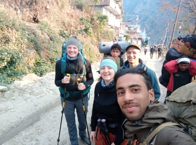 Group of hikers posing on a trail, carrying gear.
