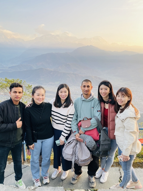 Group posing at a scenic viewpoint with mountains in the distance.