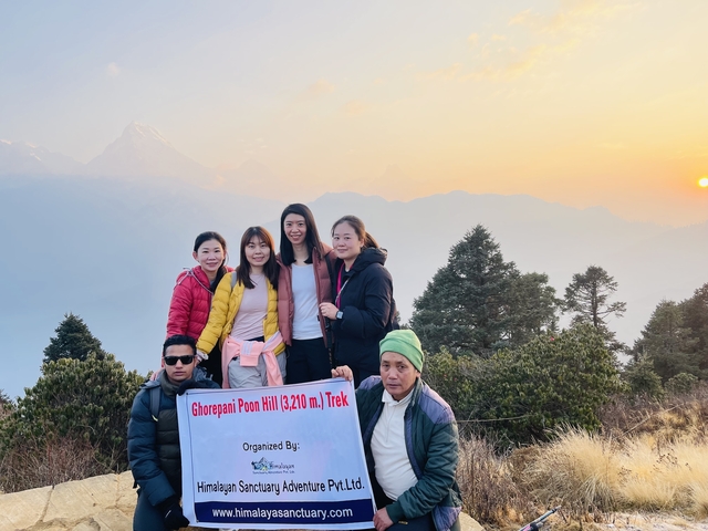 Group holding a trek sign with mountain range in the background.