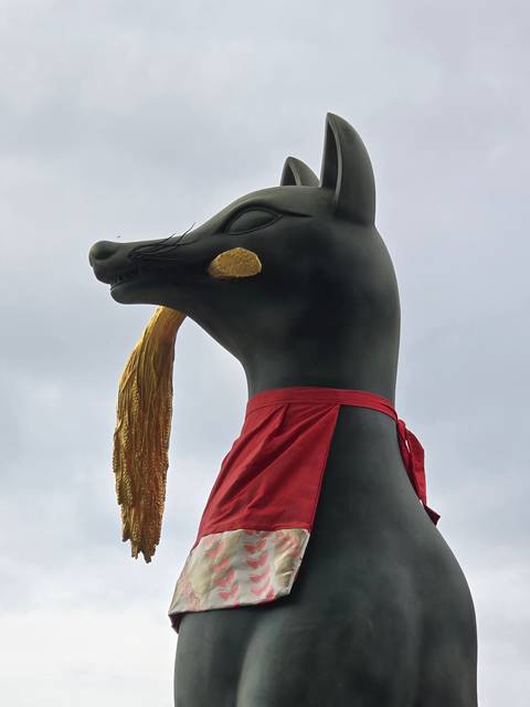 Statue of a fox with a red cloth.