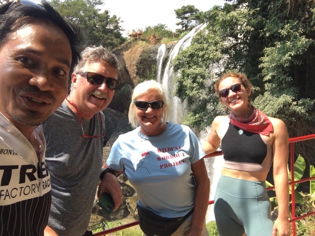 A group of people posing in front of a waterfall.