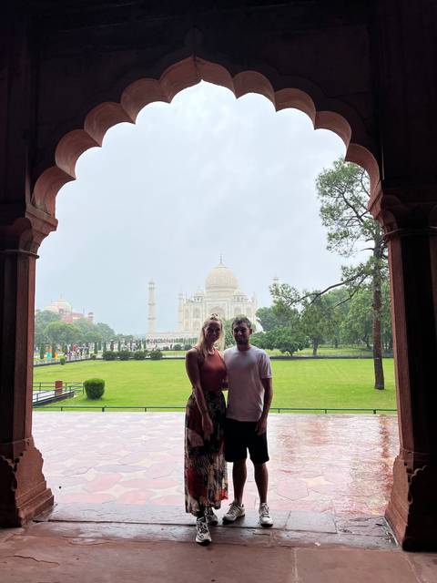Couple posing under an archway with the Taj Mahal in the background.